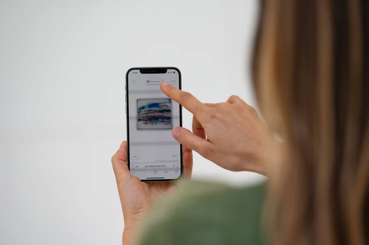 A hand holding a phone showing a PLACE MY ART artwork page